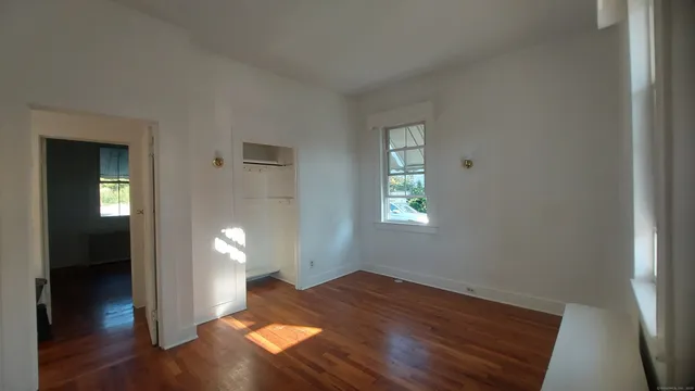 an empty room with wooden floor and windows