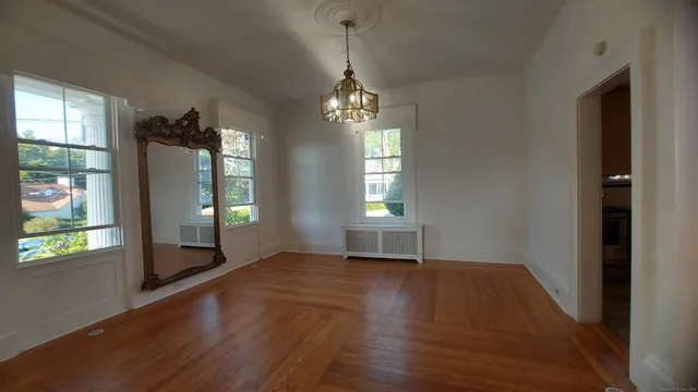 a view of an empty room with window and wooden floor