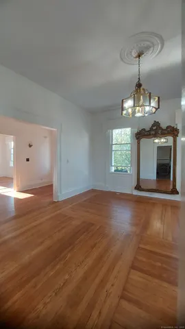 a view of an empty room with window and wooden floor