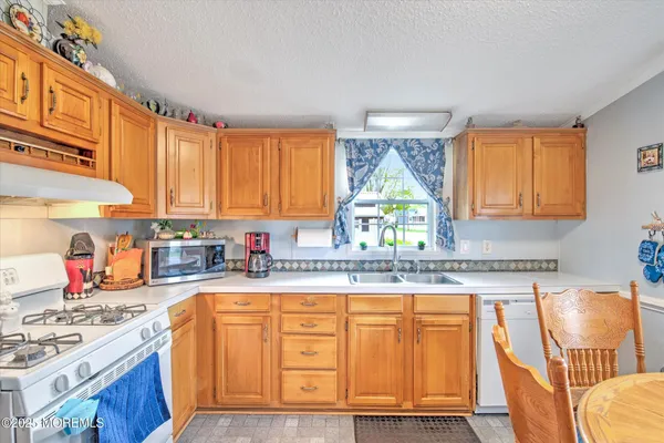 a kitchen with granite countertop a stove a sink and dishwasher wooden cabinets with wooden floor