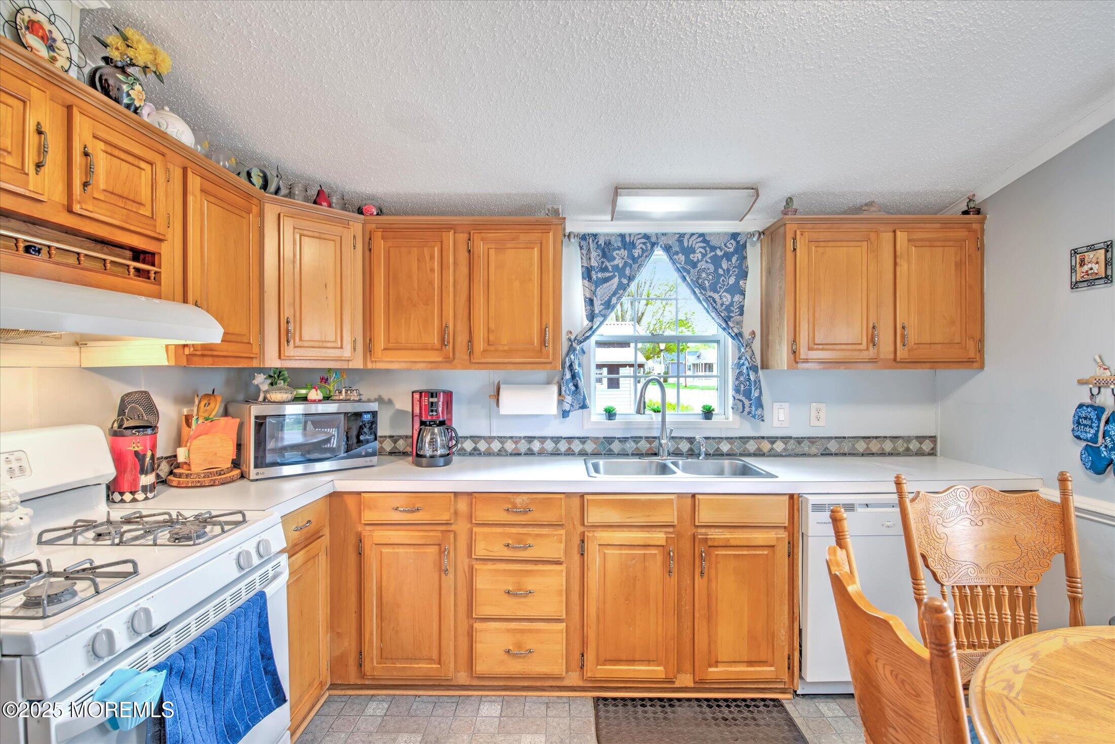 38 Village Road Morganville, NJ 07751 - Photo 14 of 20 a kitchen with granite countertop a stove a sink and dishwasher wooden cabinets with wooden floor