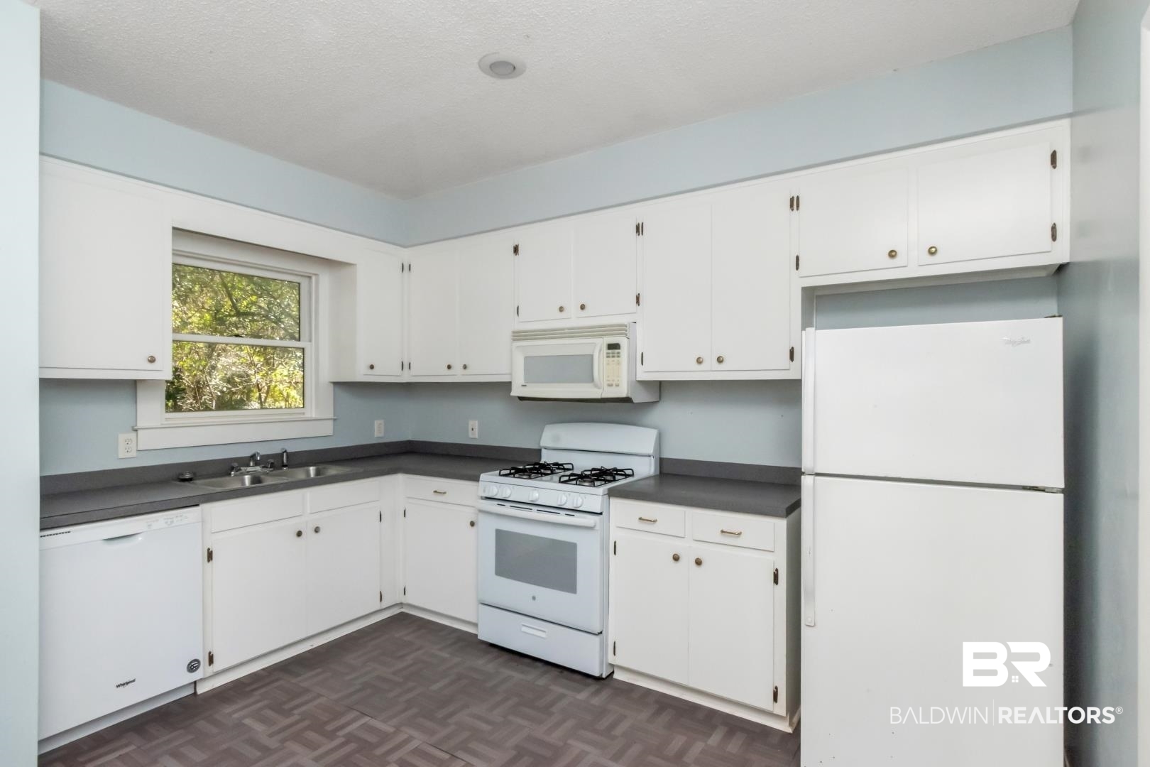 731 Jemison Street Mobile, AL 36606 - Photo 9 of 27 Kitchen with dark countertops, white appliances, white cabinetry, and a textured ceiling