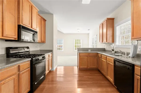 a kitchen with stainless steel appliances granite countertop a stove a sink dishwasher and a microwave oven with wooden cabinets