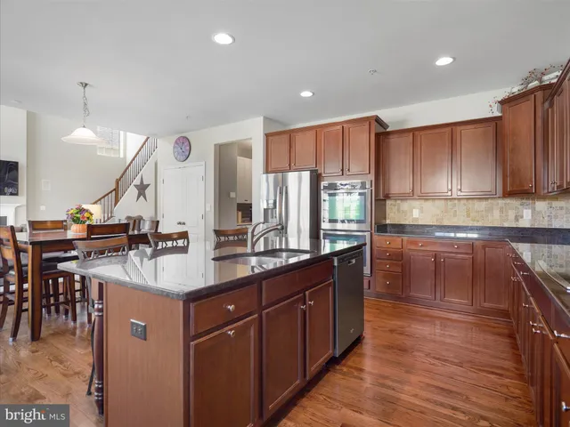 a kitchen with kitchen island granite countertop a sink a counter top space appliances and cabinets