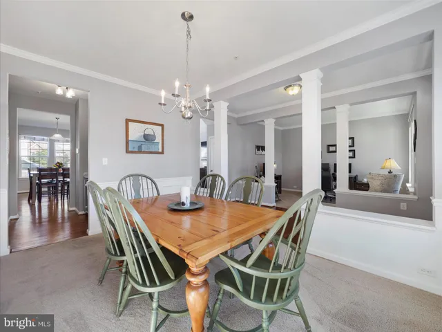 a view of a dining room and livingroom with furniture wooden floor a chandelier