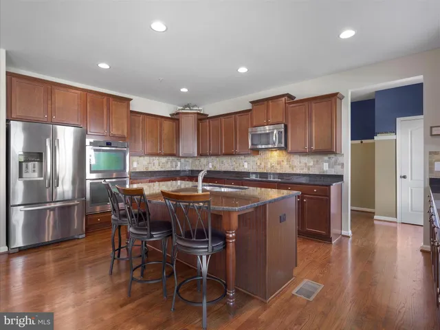 a kitchen with stainless steel appliances granite countertop a table chairs refrigerator sink and microwave