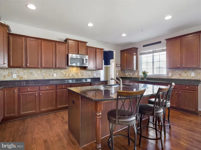 a kitchen with granite countertop wooden floors a center island and appliances