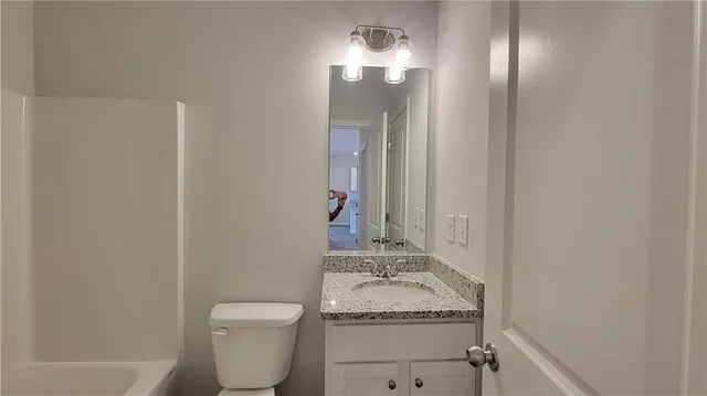 a bathroom with a granite countertop sink toilet and a mirror