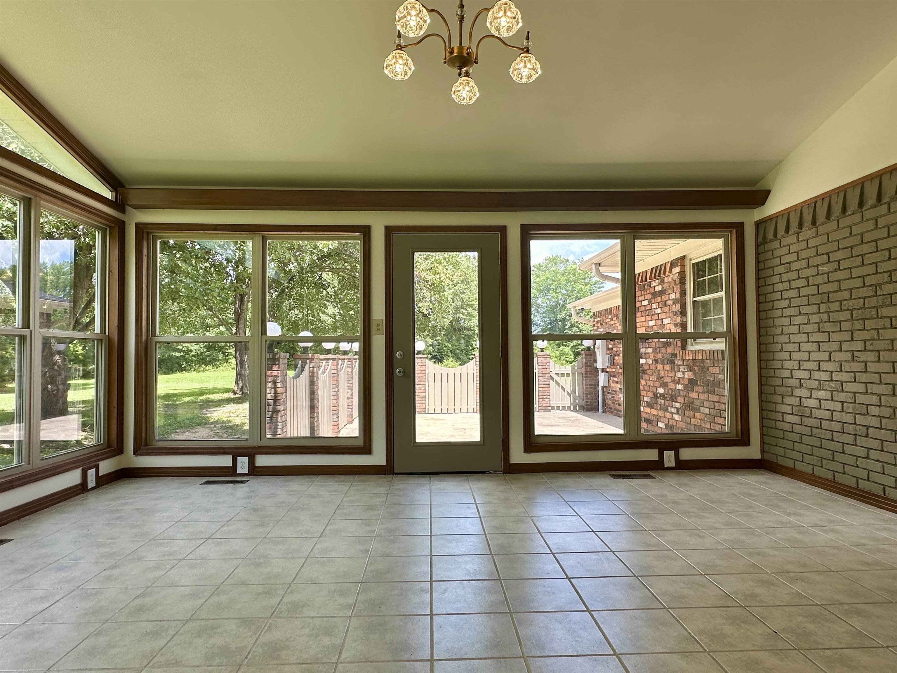 808 West Main Street Adamsville, TN 38310 - Photo 21 of 37 Unfurnished sunroom with lofted ceiling, tile patterned floors, a chandelier, and brick wall