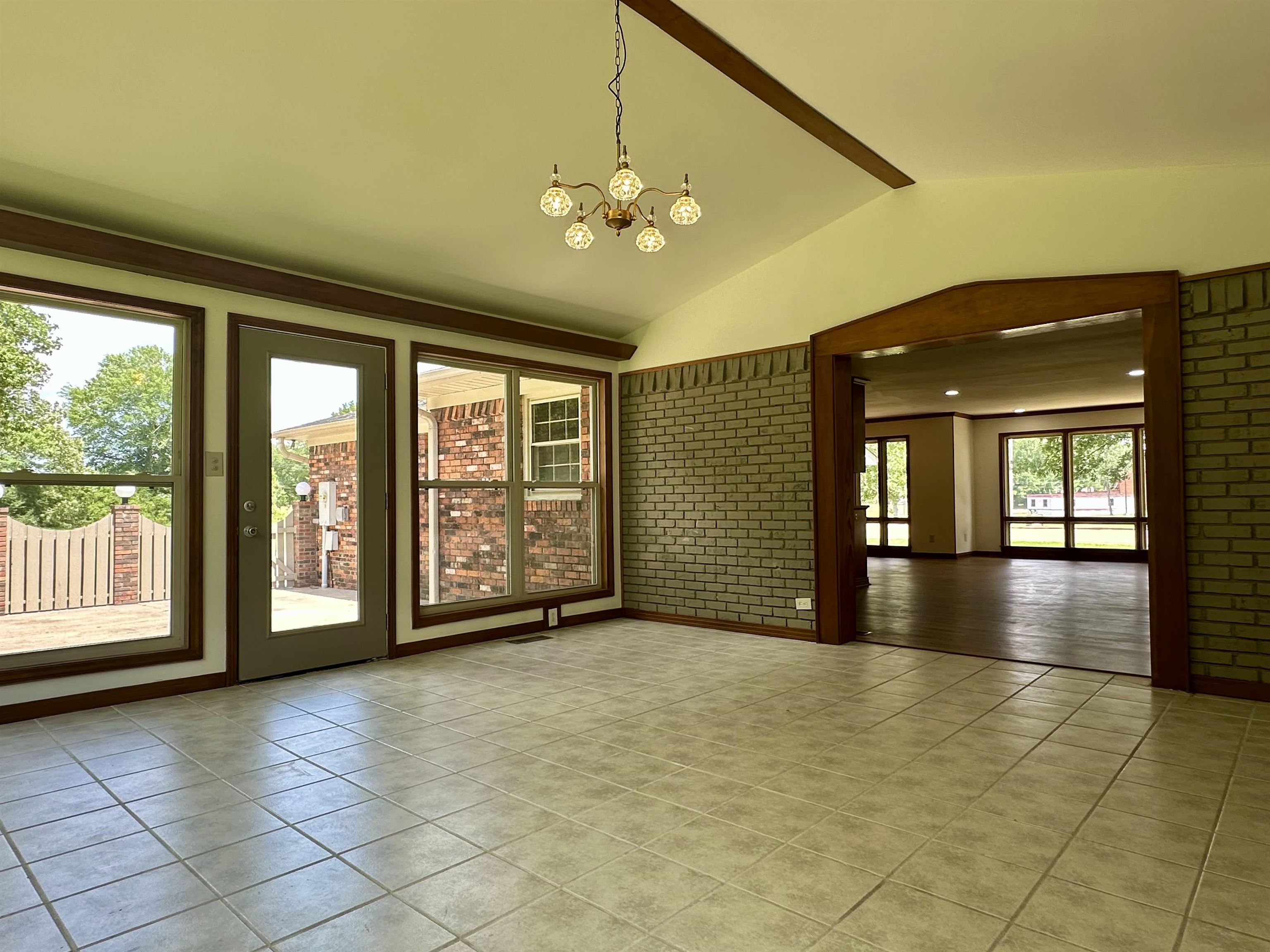 808 West Main Street Adamsville, TN 38310 - Photo 22 of 37 Empty room featuring a chandelier, tile patterned flooring, and brick wall