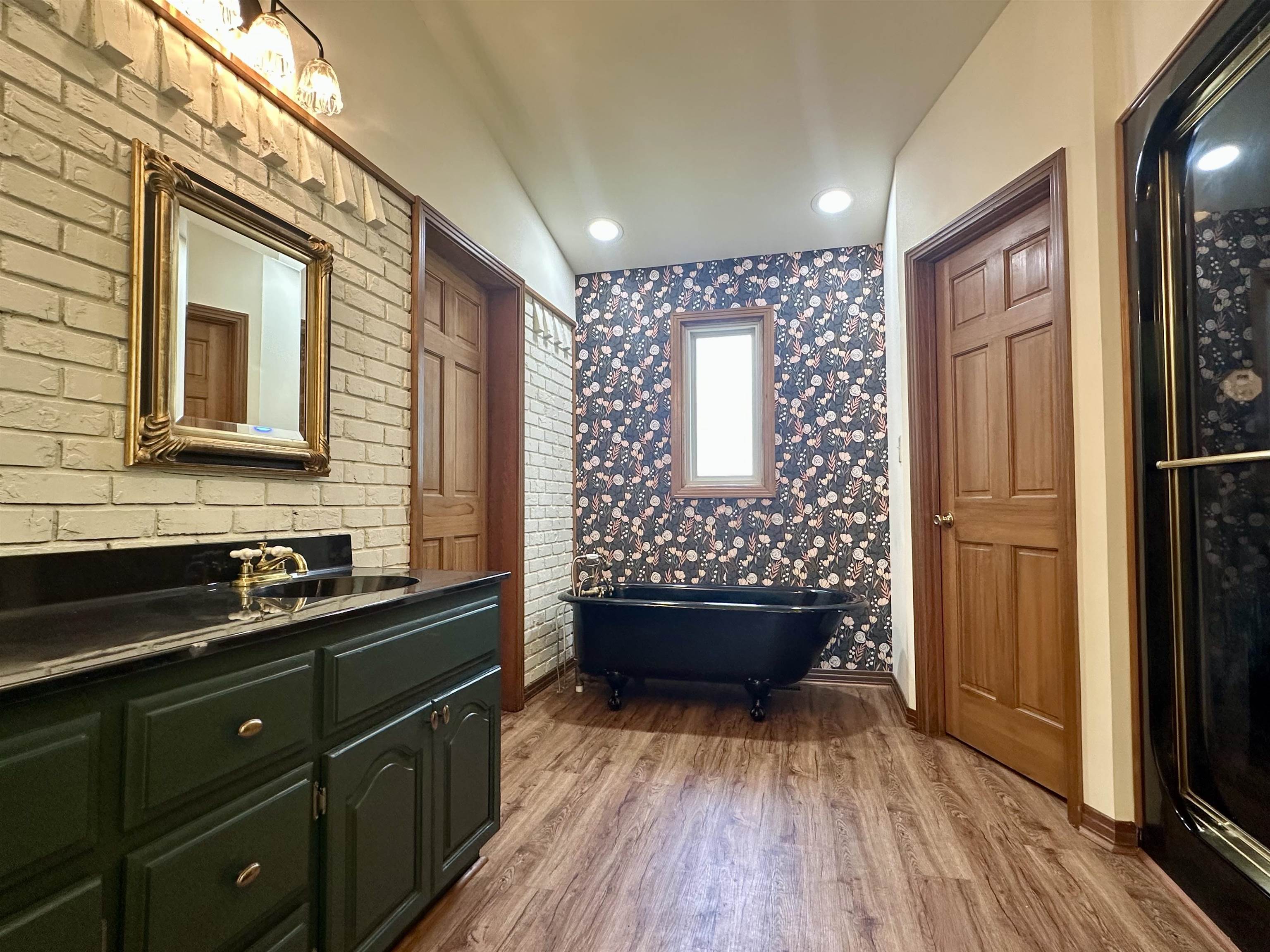 808 West Main Street Adamsville, TN 38310 - Photo 23 of 37 Bathroom with wood finished floors, a soaking tub, vanity, and wallpapered walls