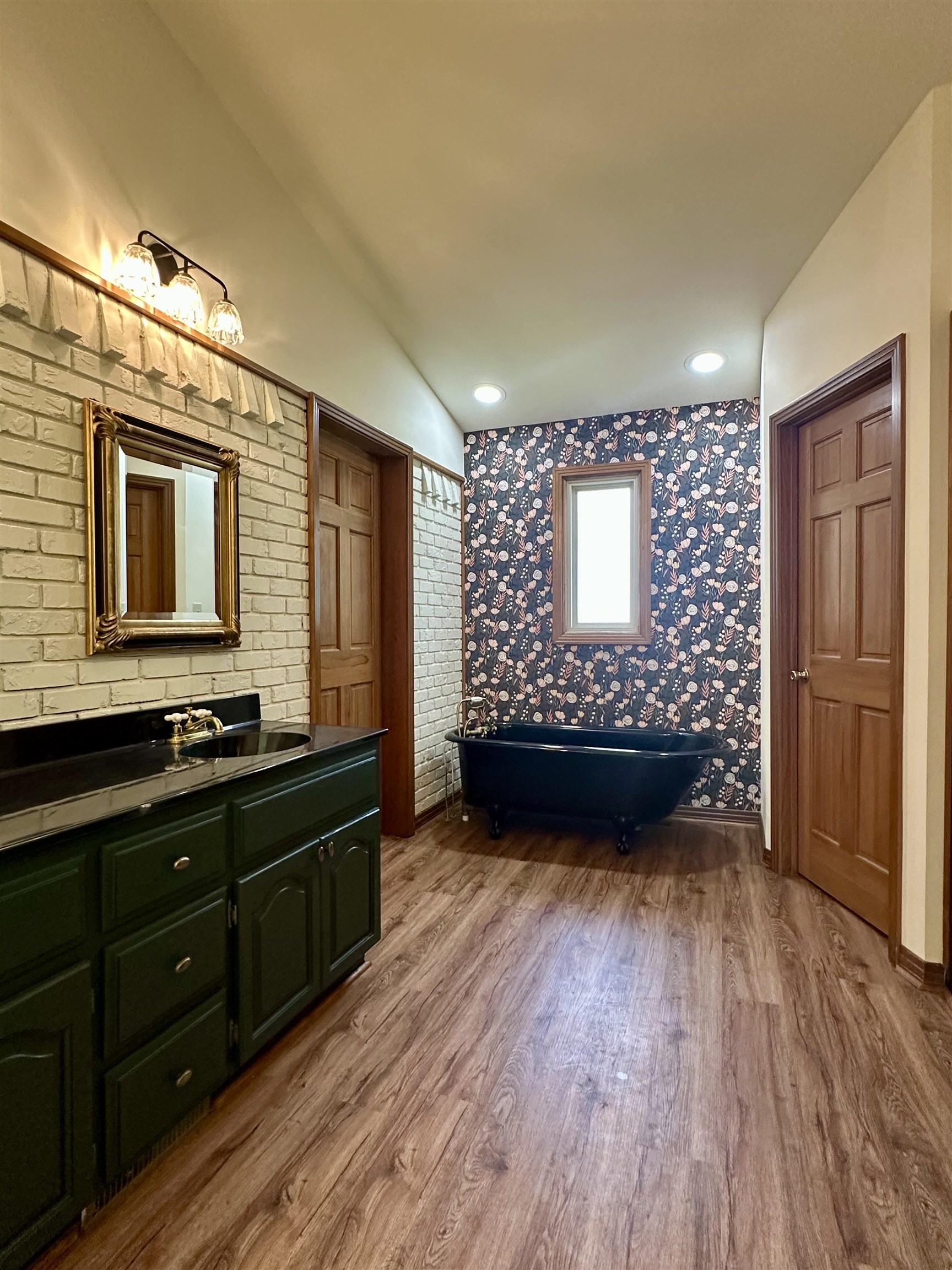 808 West Main Street Adamsville, TN 38310 - Photo 24 of 37 Bathroom featuring wood finished floors, vanity, a freestanding bath, lofted ceiling, and wallpapered walls