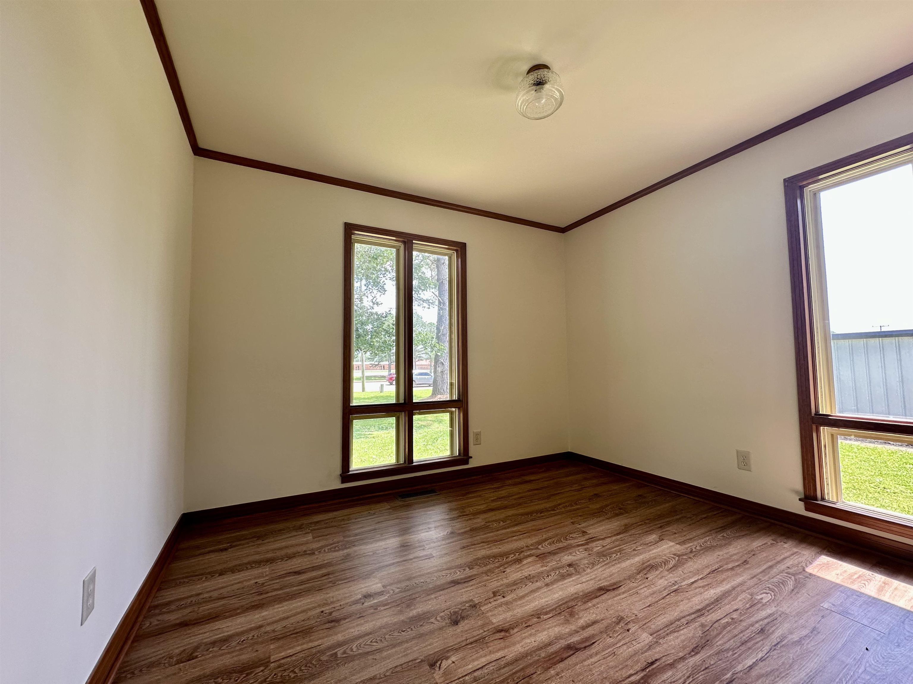 808 West Main Street Adamsville, TN 38310 - Photo 31 of 37 Empty room with crown molding, healthy amount of natural light, and dark wood-type flooring