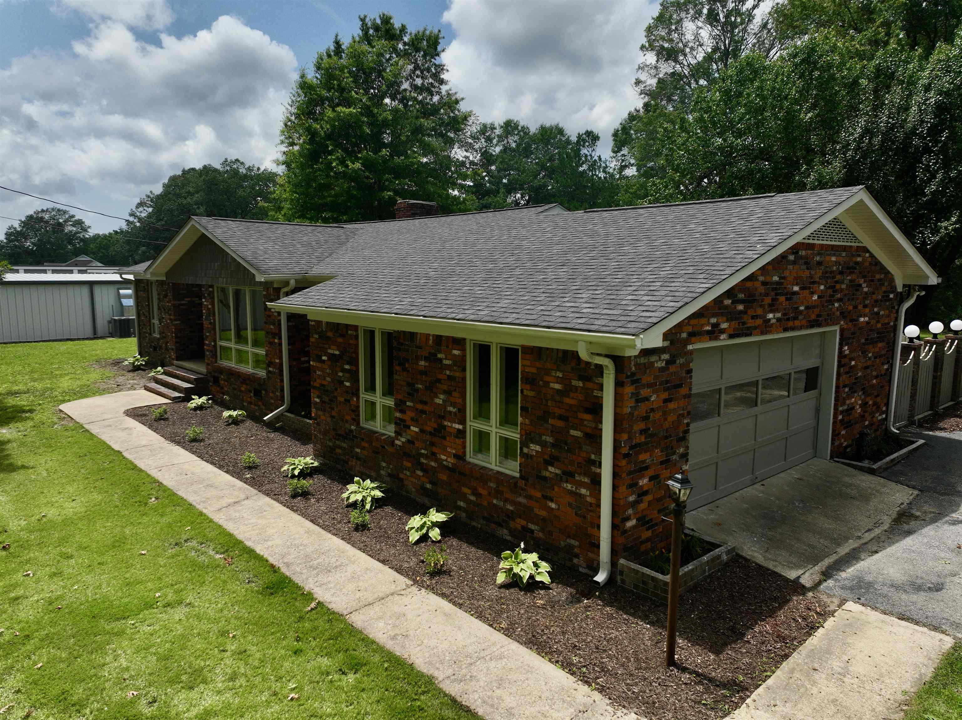 808 West Main Street Adamsville, TN 38310 - Photo 4 of 37 Ranch-style home with a shingled roof, a garage, a front lawn, brick siding, and driveway