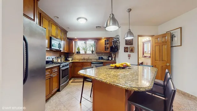 a kitchen with granite countertop kitchen island stainless steel appliances a sink stove and refrigerator