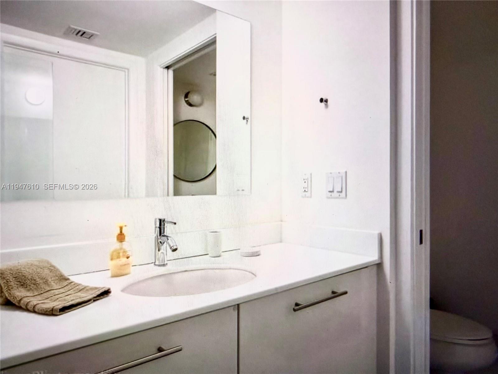 92 Southwest 3rd Street, Unit 4709 Miami, FL 33130 - Photo 7 of 18 a bathroom with a granite countertop sink and a mirror