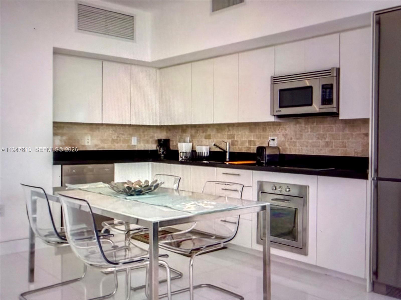 92 Southwest 3rd Street, Unit 4709 Miami, FL 33130 - Photo 8 of 18 a kitchen with stainless steel appliances kitchen island granite countertop a table and chairs