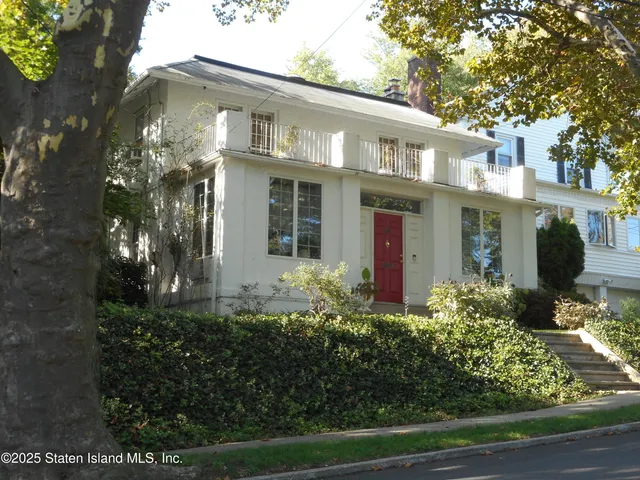 a front view of a house with lots of flowers planted