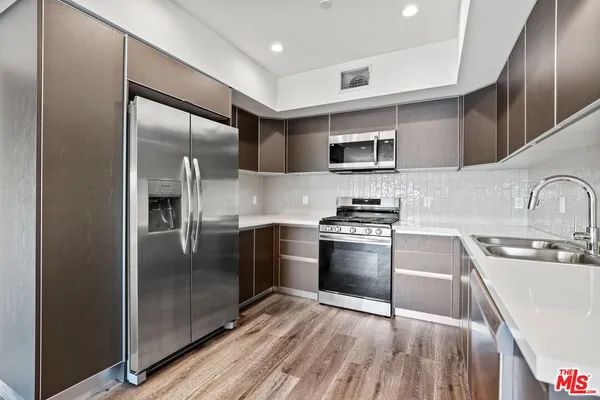 a kitchen with stainless steel appliances granite countertop a refrigerator a sink and a stove