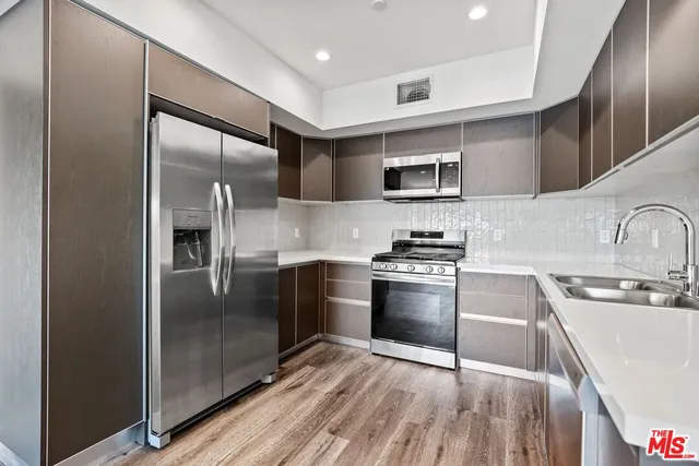 a kitchen with stainless steel appliances granite countertop a refrigerator a sink and a stove