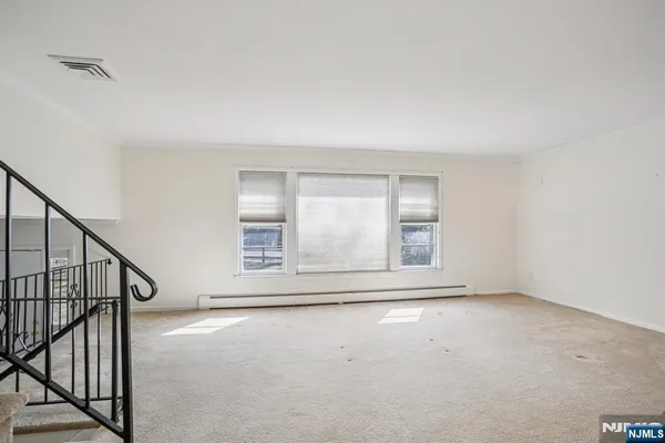a view of an empty room with wooden floor and fan