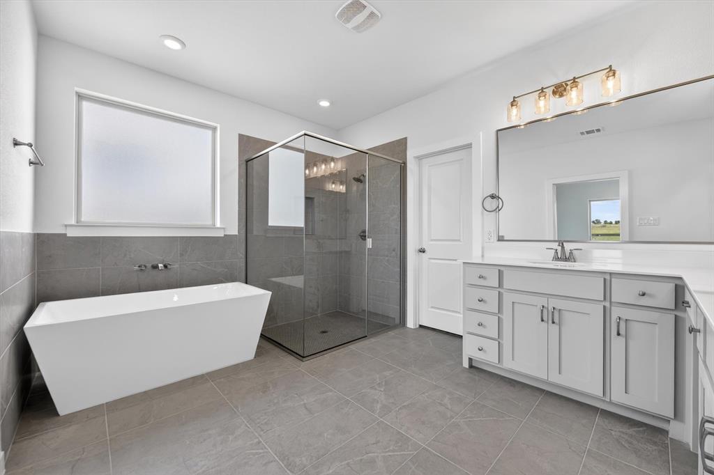 416 McAlpine Drive Springtown, TX 76082 - Photo 23 of 40 Spacious bathroom featuring a freestanding soaking tub, a frameless glass shower enclosure, and an extended vanity with dual sinks