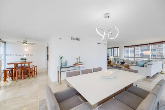 a large living room with stainless steel appliances furniture a dining table and a large window