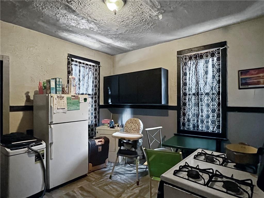 7347 Burton Street Pittsburgh, PA 15218 - Photo 15 of 31 a kitchen with a refrigerator a stove a sink and a dining table with wooden floor