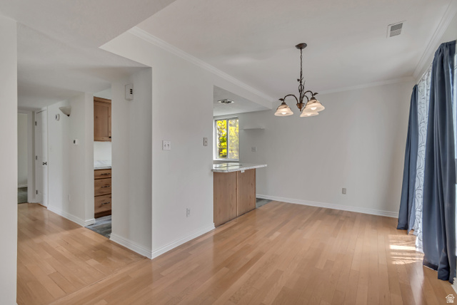 653 South 500 West, Unit 1 Provo, UT 84601 - Photo 6 of 17 Spacious room featuring wood-finish flooring, white walls, and a multi-light chandelier