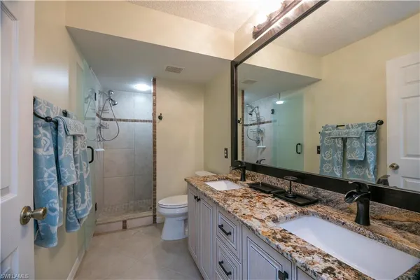 a bathroom with a granite countertop sink toilet and shower