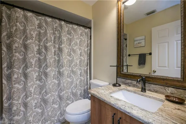 a bathroom with a granite countertop sink and a mirror