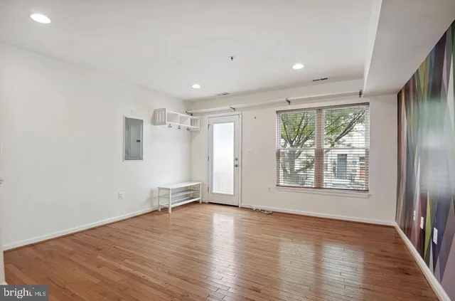 an empty room with wooden floor and windows