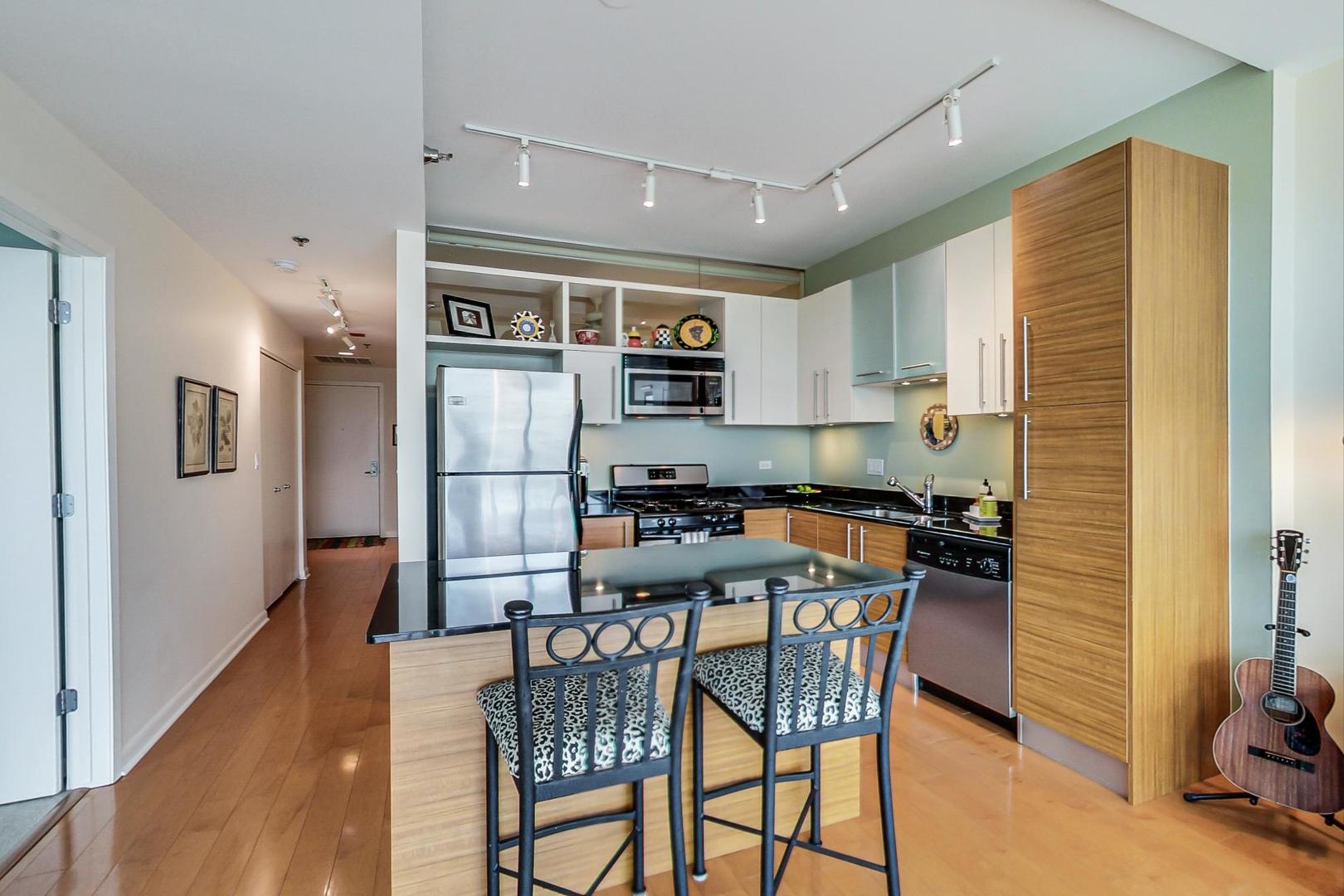 225 South Sangamon Street, Unit 809 Chicago, IL 60607 - Photo 21 of 34 a kitchen with stainless steel appliances granite countertop a dining table chairs refrigerator and sink