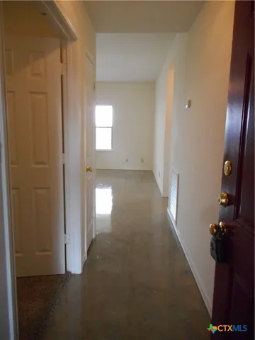 a view of a hallway with wooden floor and a bathroom