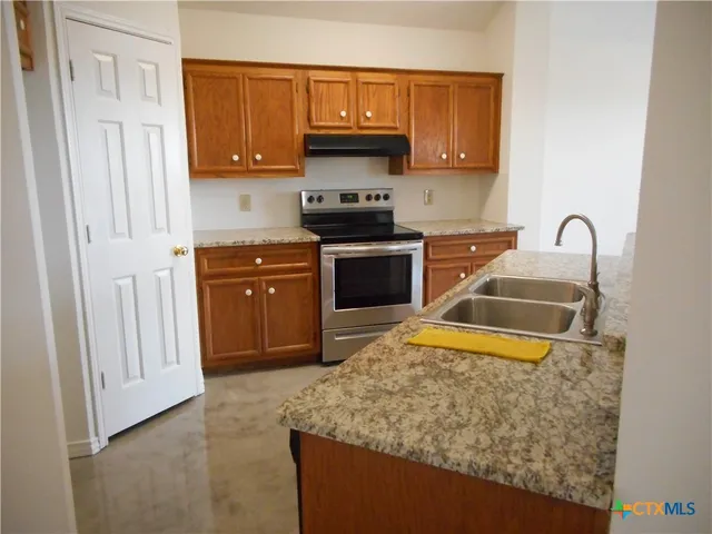 a kitchen with stainless steel appliances granite countertop a stove a sink and a microwave