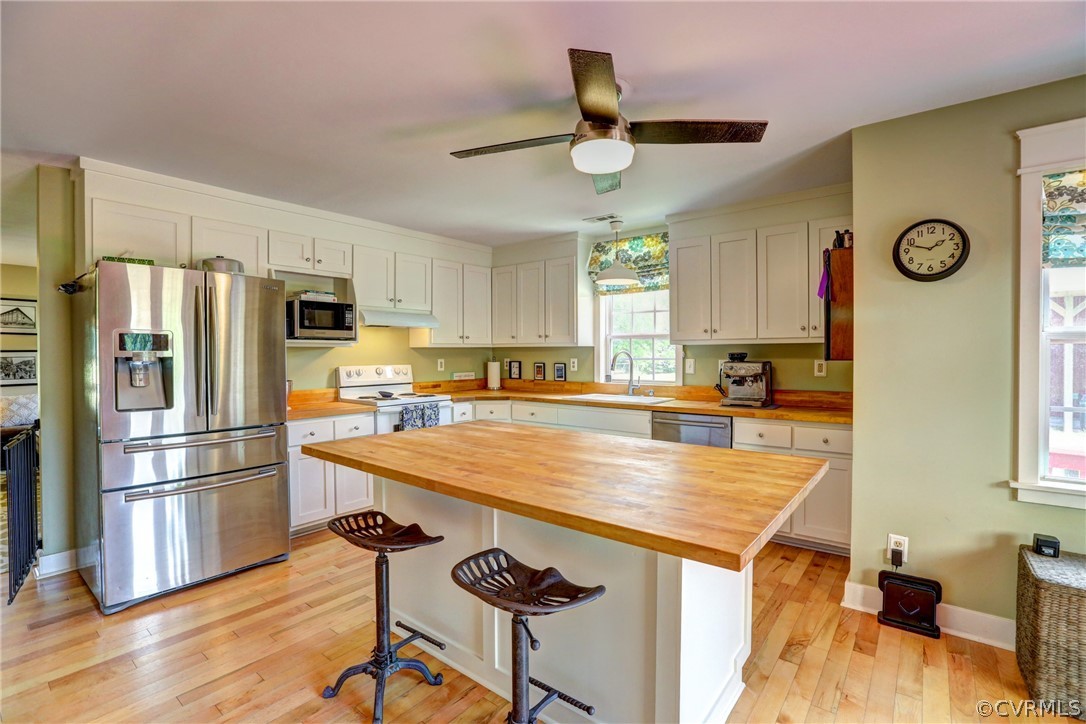 5226 North Warriner Road Richmond, VA 23231 - Photo 15 of 50 a kitchen with stainless steel appliances granite countertop a refrigerator a stove a sink a dining table and chairs with wooden floor