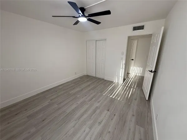 an empty room with wooden floor and a ceiling fan
