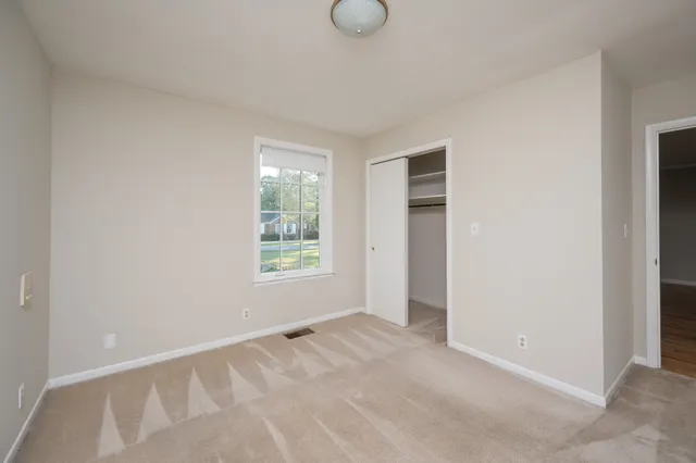 a view of an empty room with window and closet area