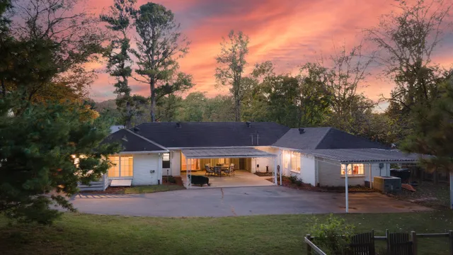 a view of house with a big yard and large trees