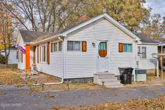 a view of a house with a yard and large tree