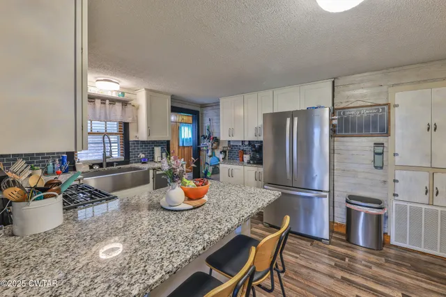 a kitchen with a refrigerator a stove and a sink with wooden floor