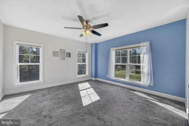 an empty room with windows and ceiling fan