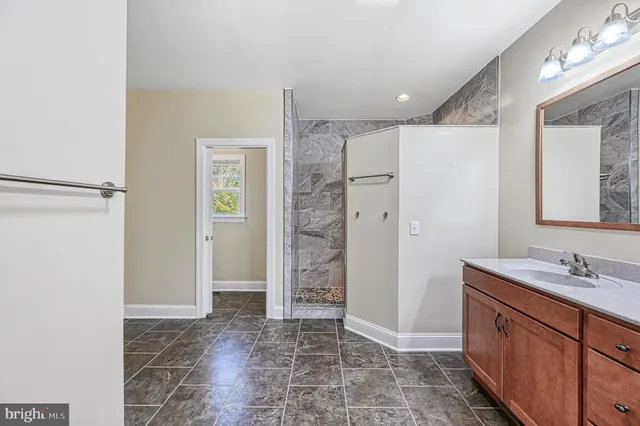 a bathroom with a granite countertop sink a mirror and a shower