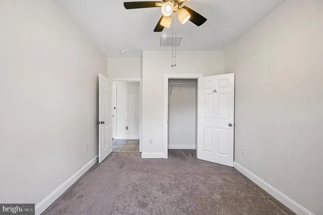 a view of an empty room and chandelier fan