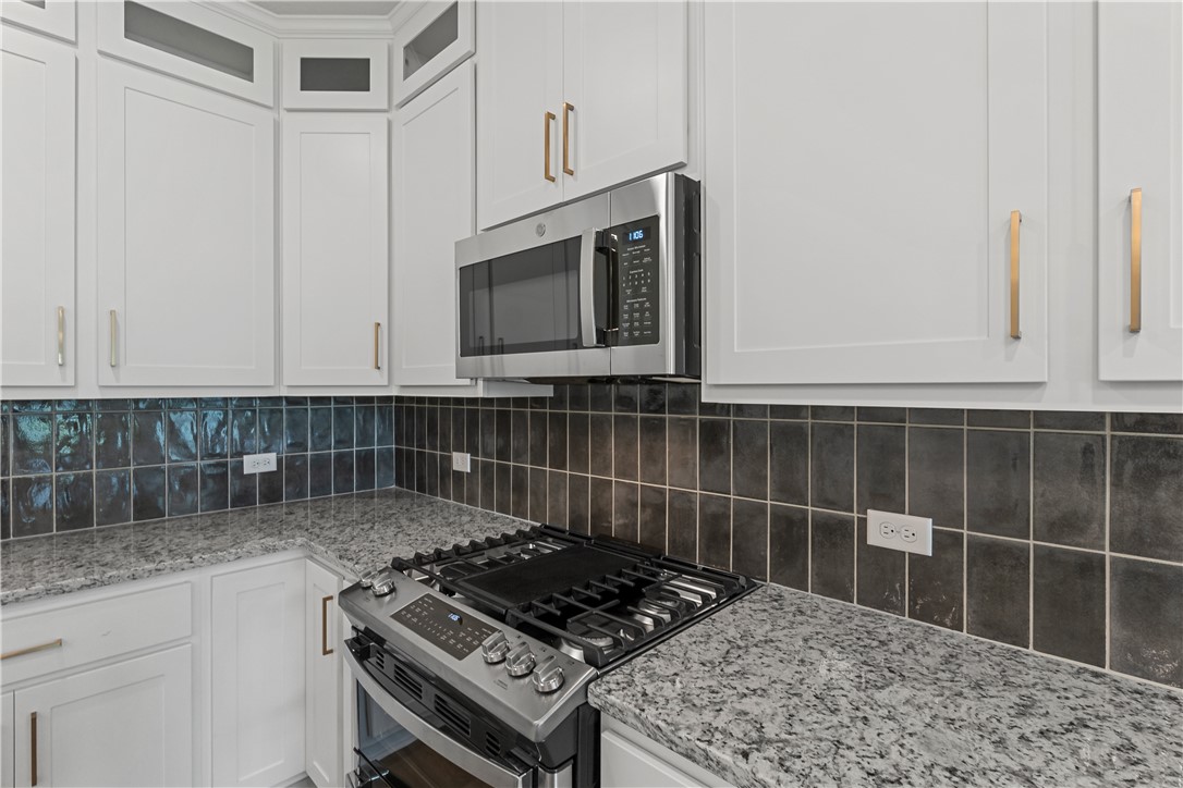 5008 Toscana Loop Bryan, TX 77802 - Photo 11 of 33 a kitchen with granite countertop a stove a sink and a microwave
