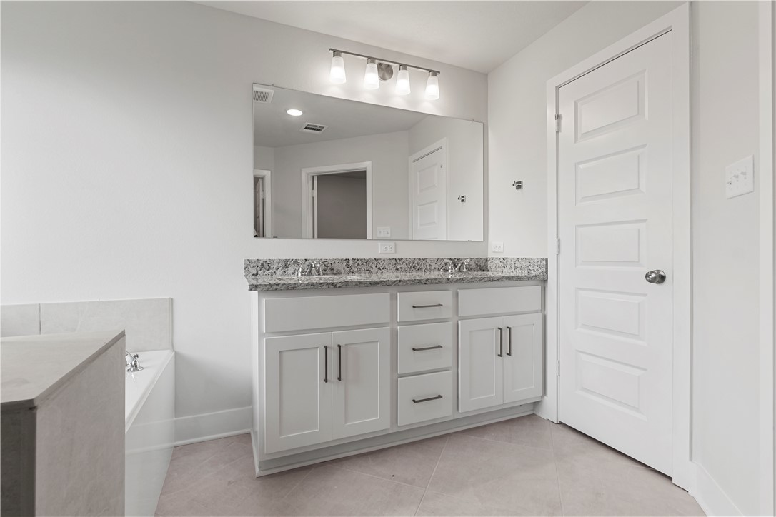 5008 Toscana Loop Bryan, TX 77802 - Photo 26 of 33 a spacious bathroom with a granite countertop sink and a mirror