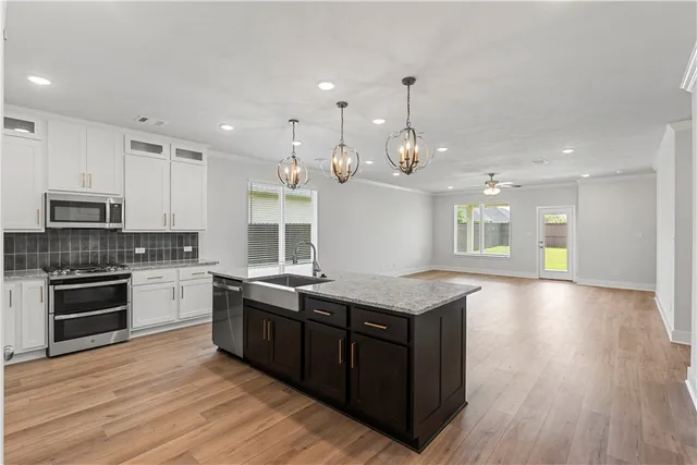 a large kitchen with granite countertop a sink dishwasher a stove and a dining table with wooden floor