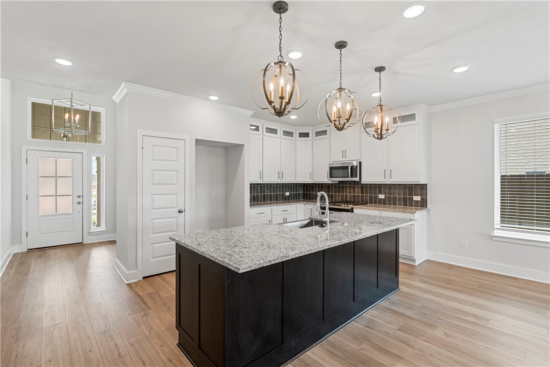 5008 Toscana Loop Bryan, TX 77802 - Photo 8 of 33 a large kitchen with granite countertop a sink dishwasher a stove and a dining table with wooden floor
