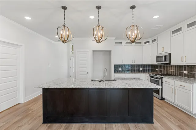 a kitchen with a sink and dishwasher with white cabinets