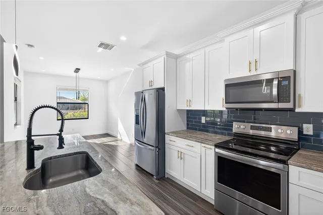 a kitchen with stainless steel appliances a stove a sink a microwave and refrigerator